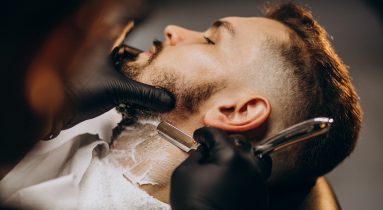 Handsome man cutting beard at a barber shop salon